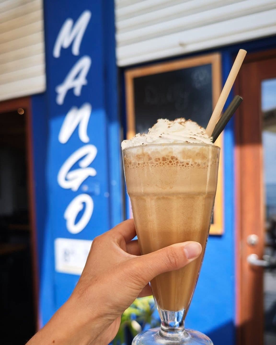 Frappé de café frente al rótulo de Mango Beach House, Torrevieja